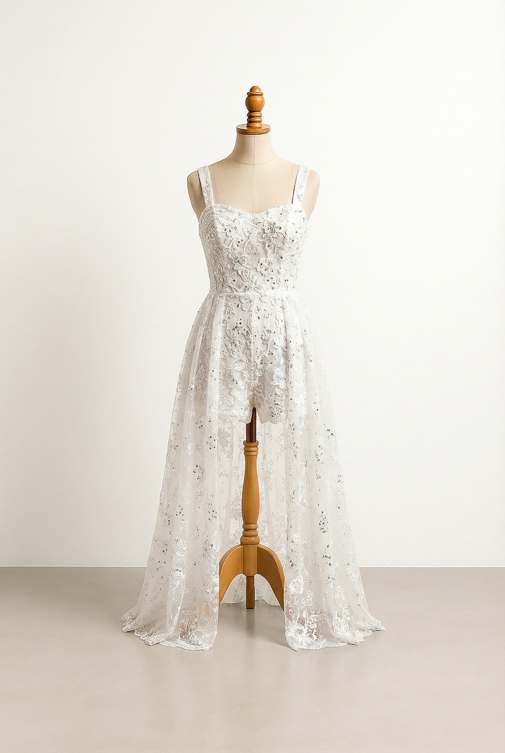 A white romper with shorts that has an attachable Lacey shear skirt attached. Flowery design with lace and sparkles, with matching silver details on the bodice.