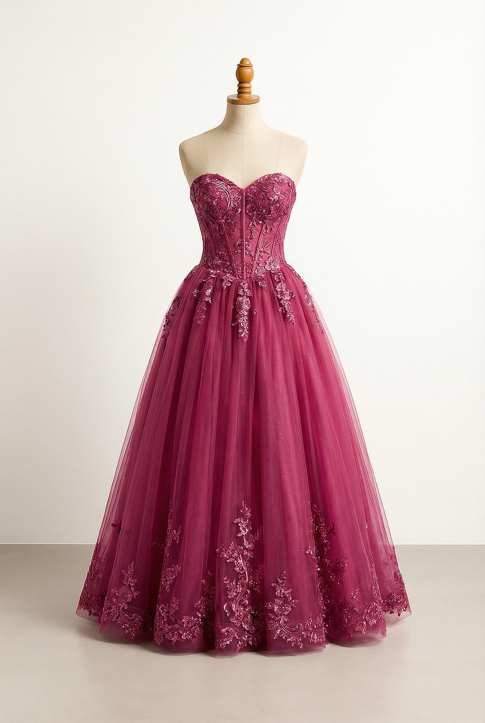 floor-length, sparkling berry magenta gown, featuring a strapless sweetheart neckline with a snatched corset bodice made of intricate applique fabric, flowing into a tulle skirt