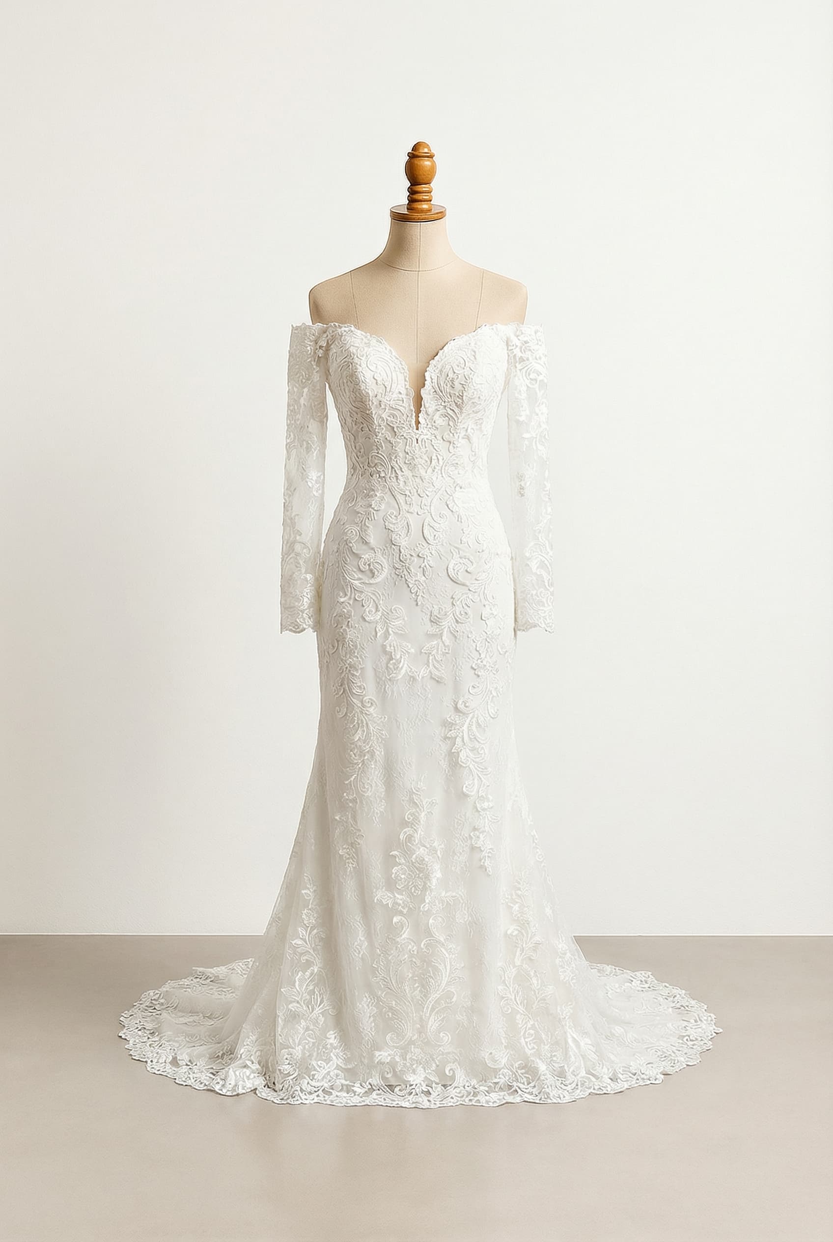 Wedding dress with an off-the-shoulder sweetheart neckline, long sleeves, lace details, a sheath silhouette, and a cathedral length skirt.