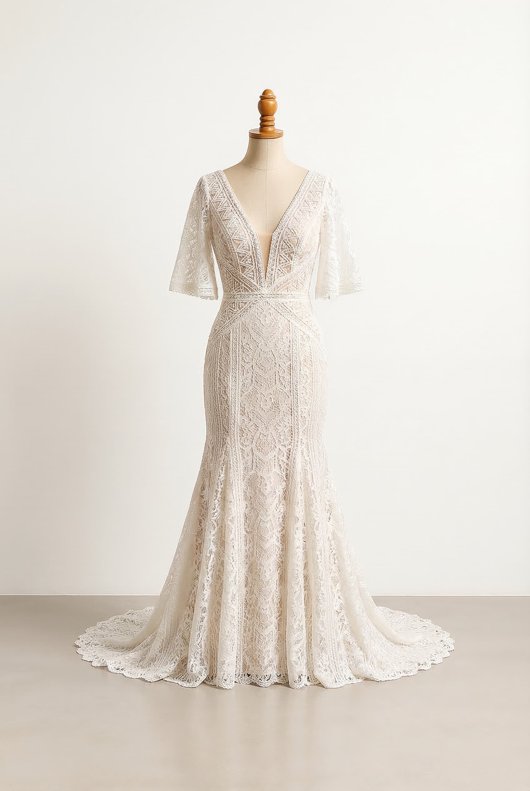 Deep ivory fit and flare or trumpet dress with lace bodice and elbow length flutter sleeve with lace trim and deep v neck, geometric lace appliqués strategically placed over a nude lining, emphasizing the décolletage and waist
