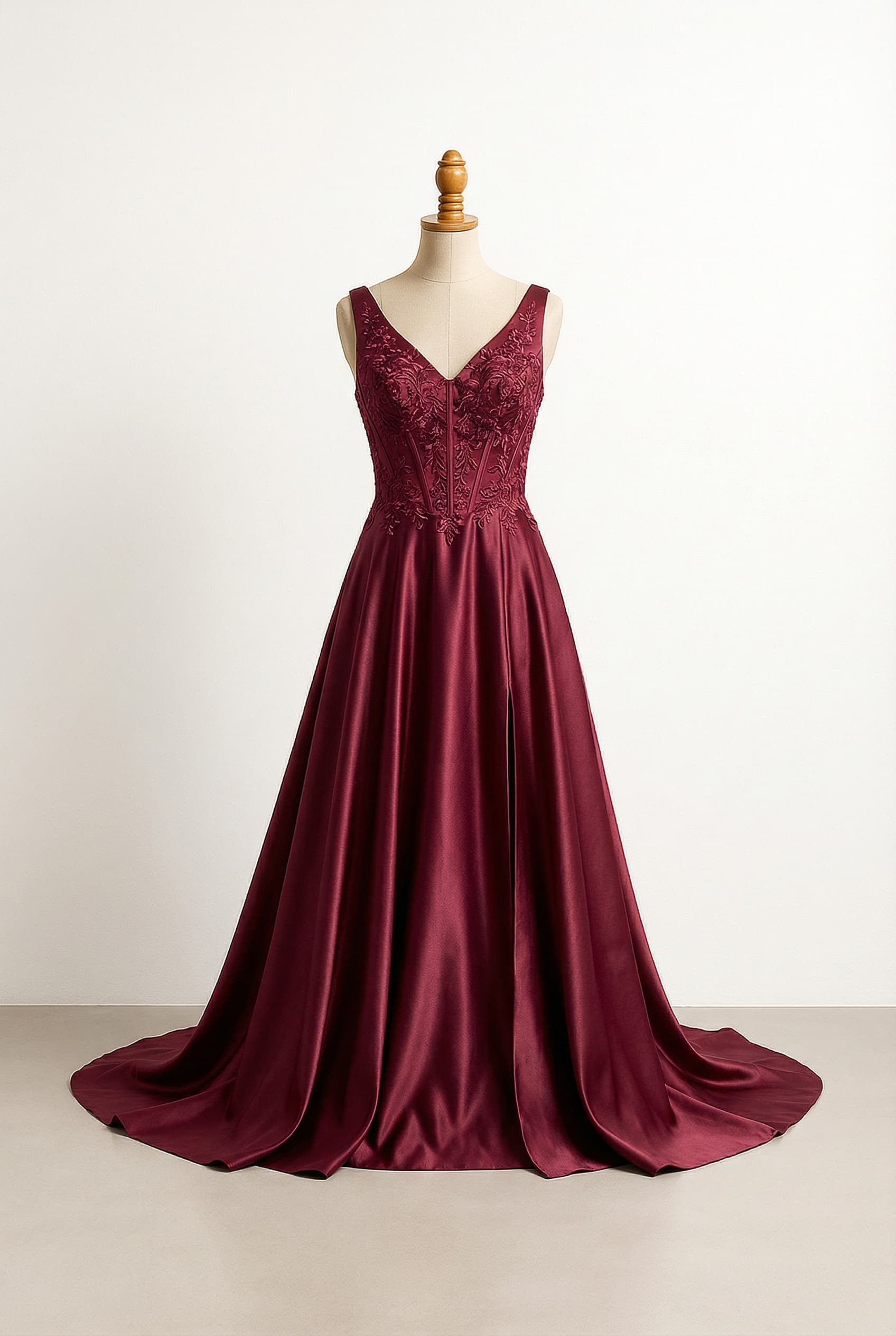 Burgundy A-line prom dress with spaghetti straps, a mesh corset bodice featuring appliquéd and beaded embroidery, a slit, and a sweep train