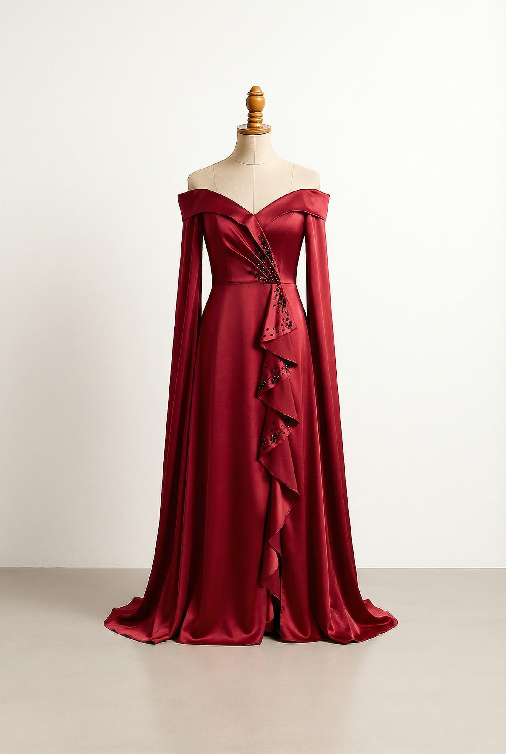 A-line floor-length prom dress in vampire red satin, featuring a V-neckline with black bead accents, ruffles flowing down the middle from the V-neck, and off-the-shoulder long flowy sleeves with black bead accents.