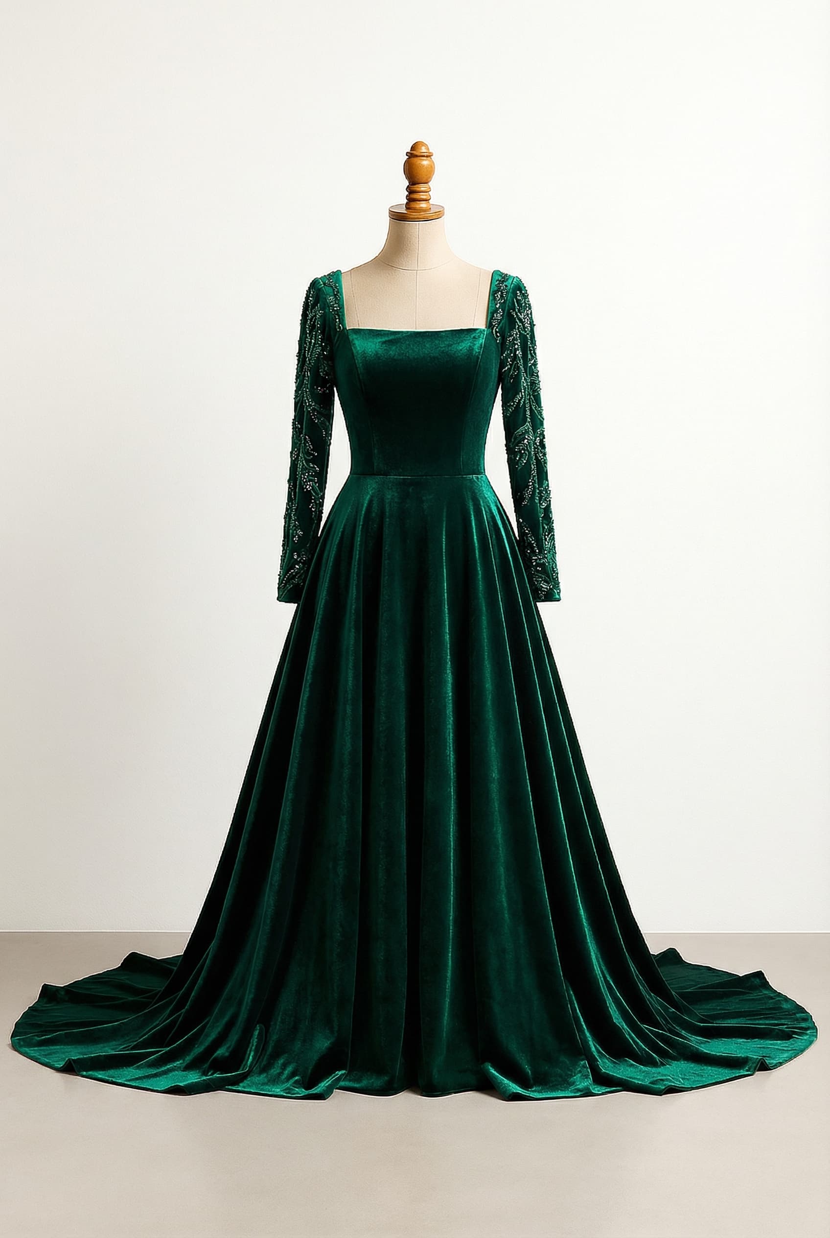 A glamorous prom dress, featuring an emerald color, royal length with a very long, dramatic train, long full-length sleeves, a straight horizontal neckline across the chest, a ball gown / princess silhouette with a fitted bodice and a full, voluminous skirt, made from velvet fabric.