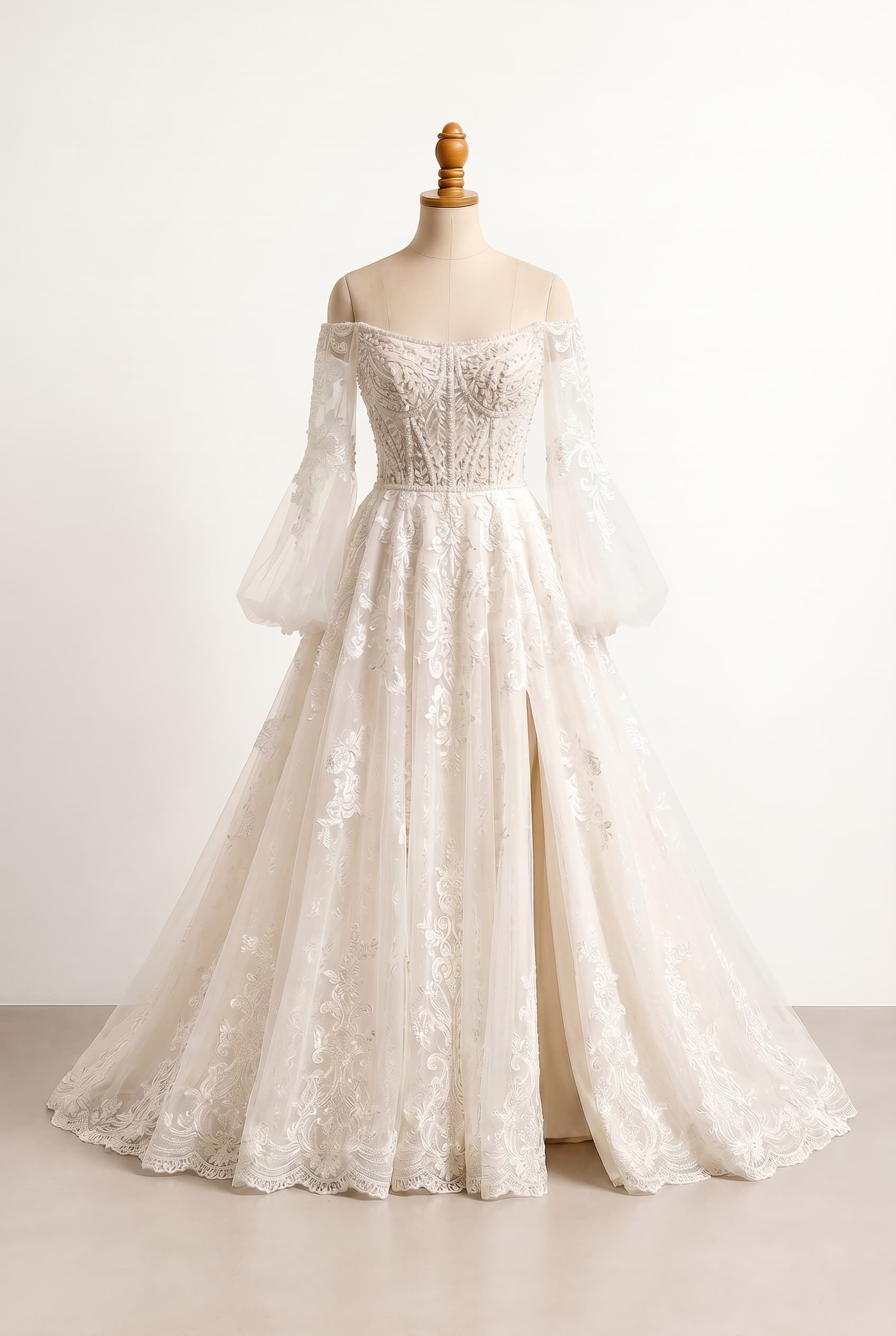 Balanced wedding dress with a fairytale aesthetic featuring a voluminous A-line silhouette in tulle fabric, structured bodice with beadwork, off-shoulder neckline with sleeves connected under the armpit, and a skirt overlaid with lace in Soft Ivory featuring a high leg slit