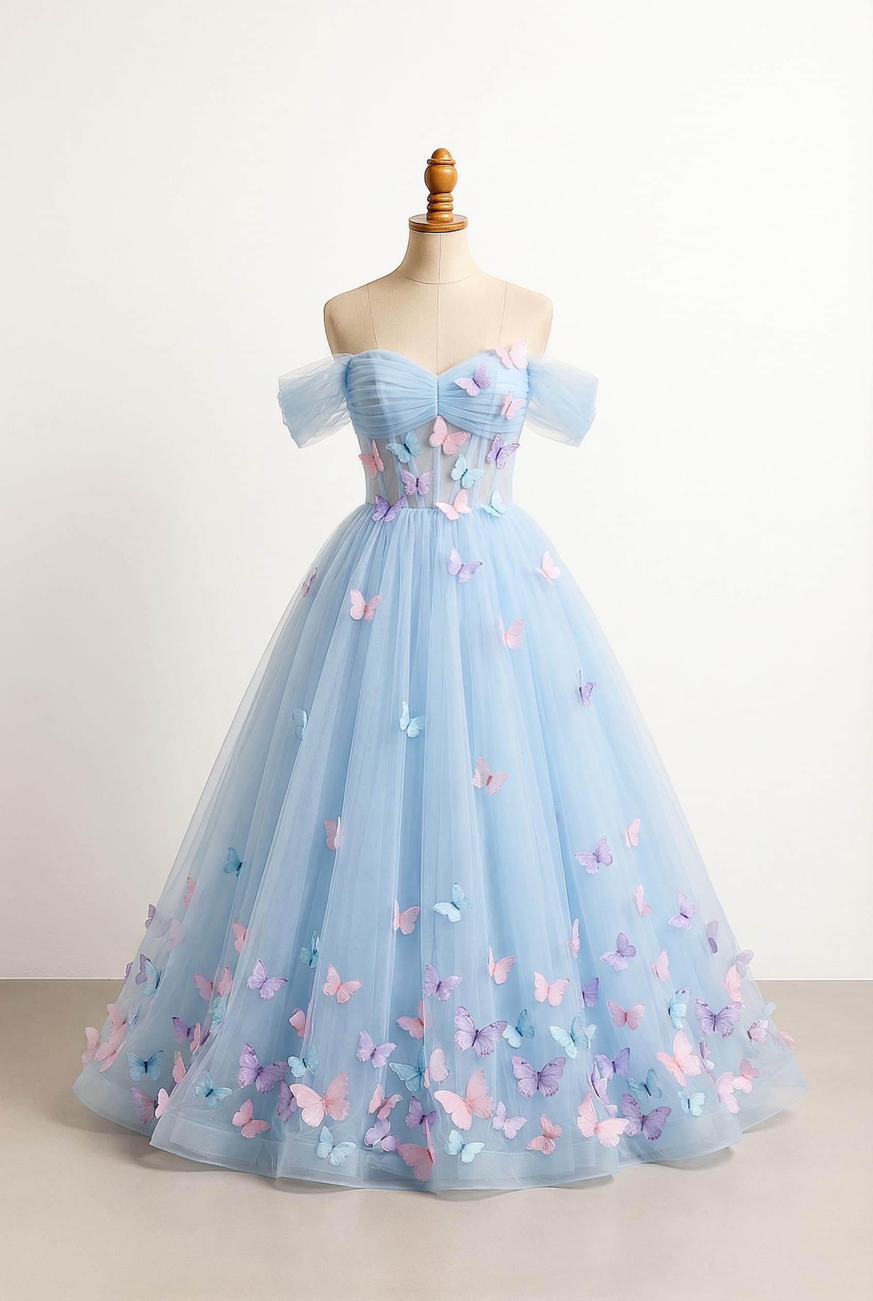 Ball gown length dress with a sweetheart neckline and off-the-shoulder sleeves. Pastel blue tulle fabric with butterfly appliques in pastel pink, pastel purple, and pastel blue on the bust and torso, with the appliques concentrated at the bottom of the skirt. Horizontal tulle detail around the bust.