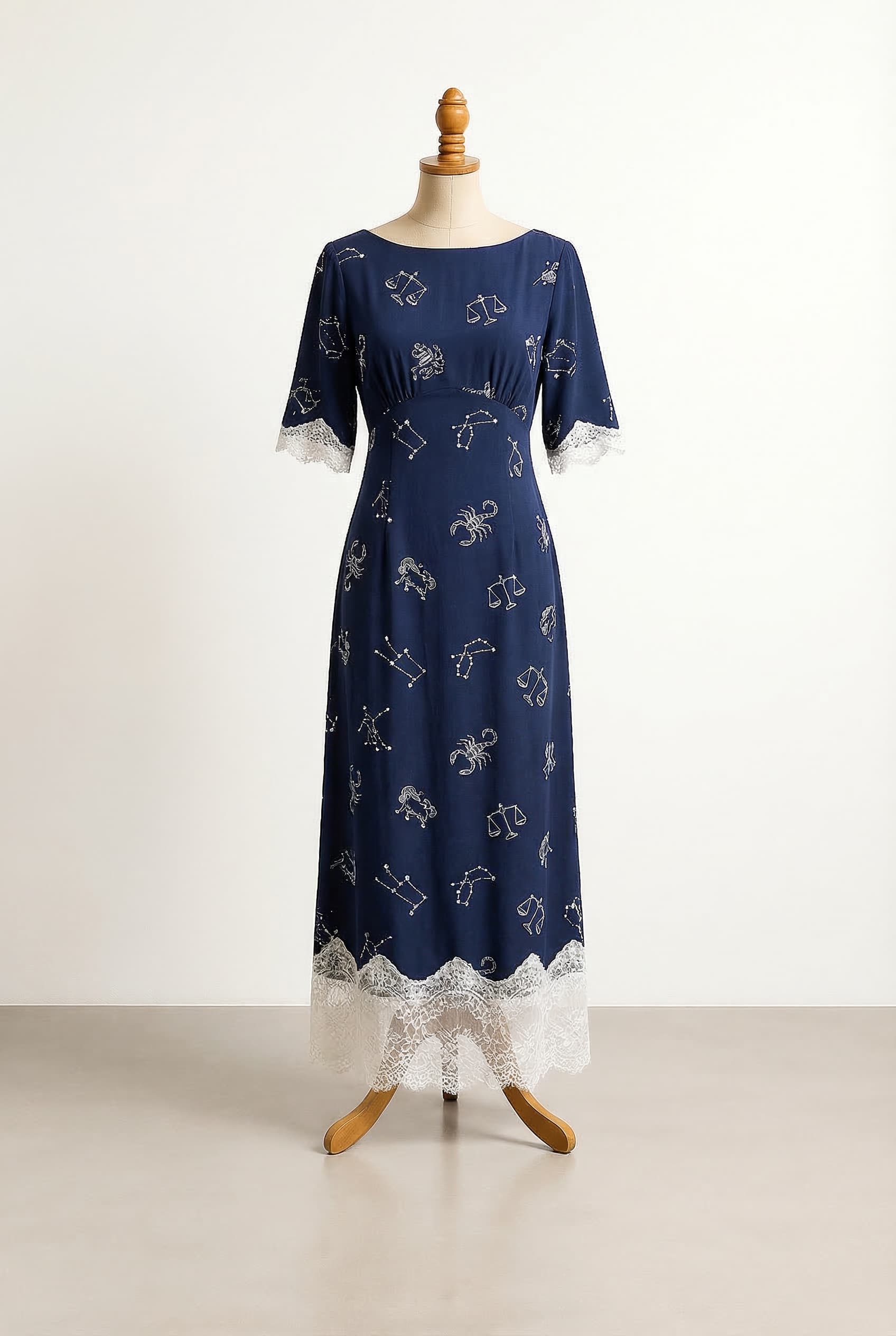 I want a balanced custom dress in Navy blue Ankle length Elbow sleeves Boat neckline Sheath silhouette Crepe de Chine fabric with astrological patterns in white with beautiful white lace near the sleeves and the bottom of the maxi skirt Empire waist