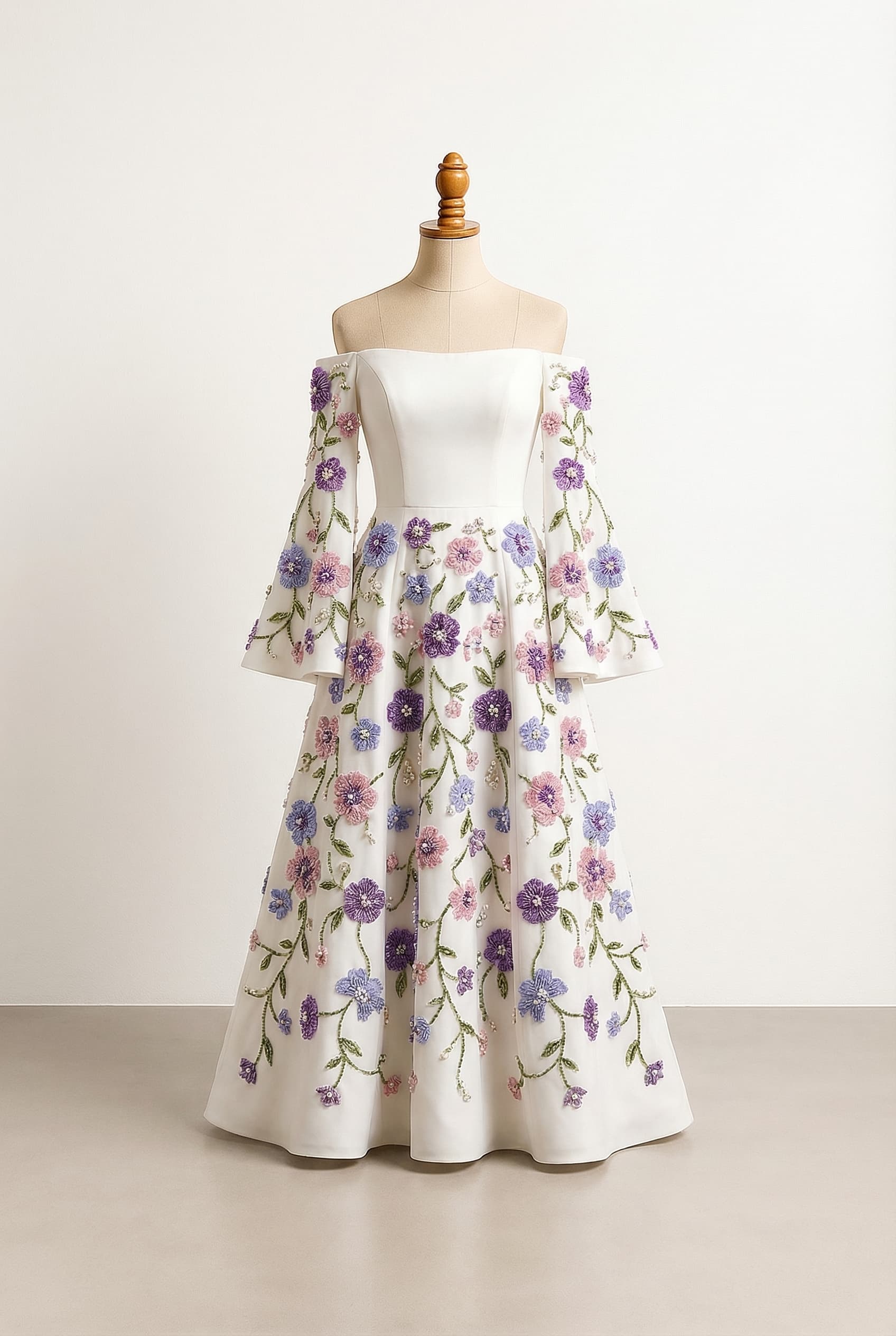 White off the shoulder a line dress with small floral motifs from the waist to the floor The sleeves start at the middle of the upper arm and flow to the wrists/hands The floral embellishments should be purple, pink and periwinkle with green vines/leaves as an accent, with the floral embellishment also on the sleeves The sleeves should be wide and flowy at the hands. V-shaped neckline at the bust. Lace fabric.