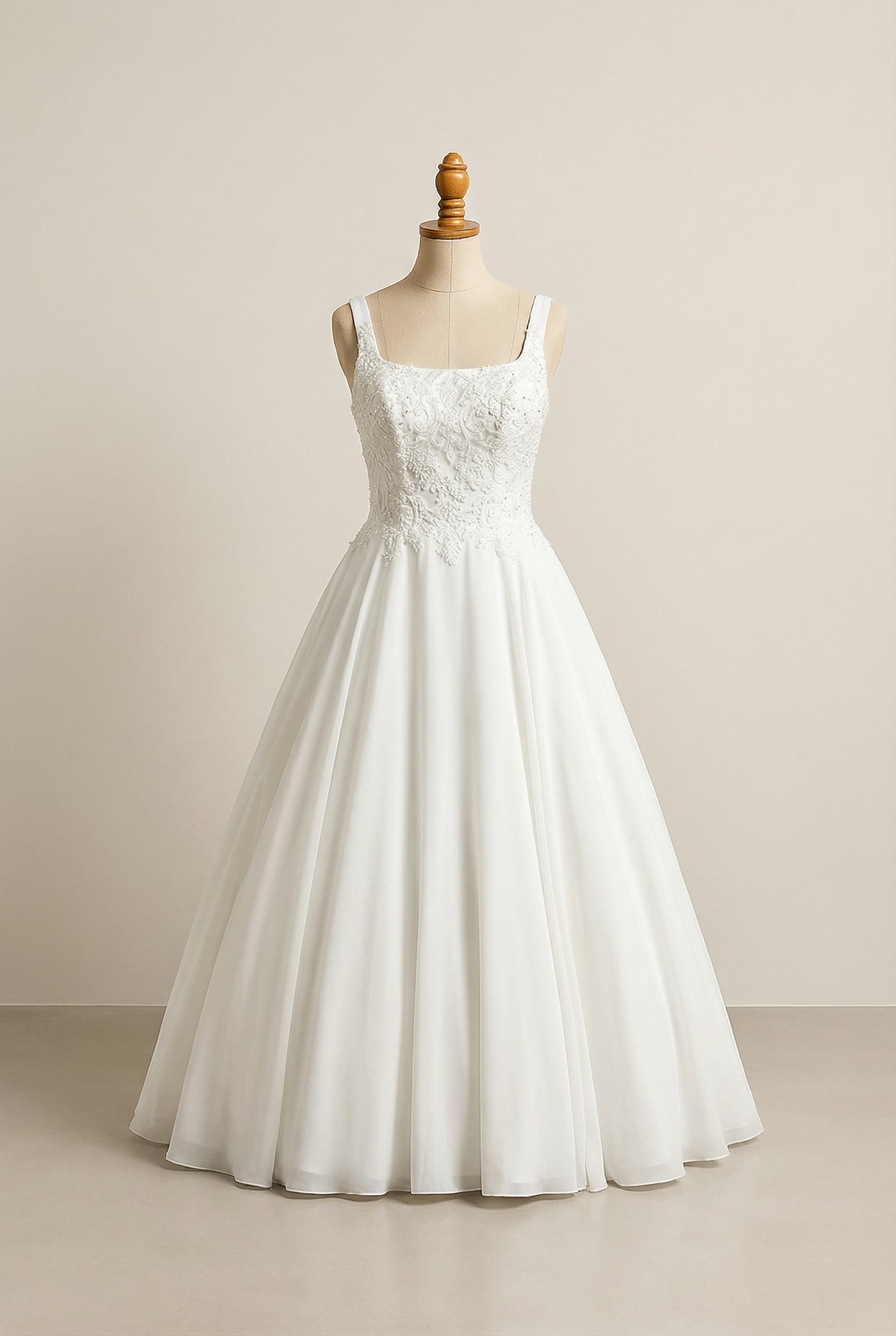 A romantic wedding dress with elegant details, featuring a white, floor-length ball gown silhouette with a side basque skirt, a square neckline with 2-3 finger width straps (not spaghetti straps), a soft, flowing fabric, and lace or a combination of lace and beading mostly at the top.