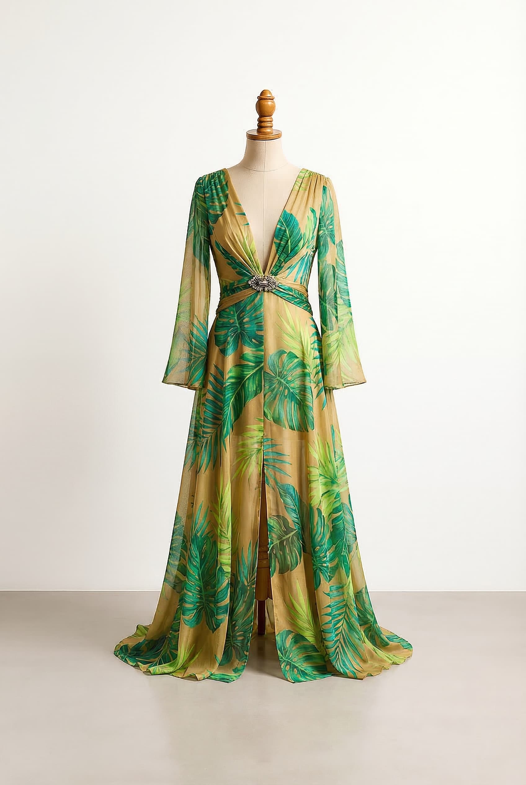 Flowing tropical-print silk chiffon gown with a plunging navel-deep neckline and a dramatically open front Bodice formed by two narrow draped panels that cross slightly at the waist and are secured with a jeweled brooch at the center Long sheer and slightly flared sleeves Lightweight and semi-transparent skirt with a high slit Vivid green jungle leaf pattern with gradients of emerald lime and teal Gold color