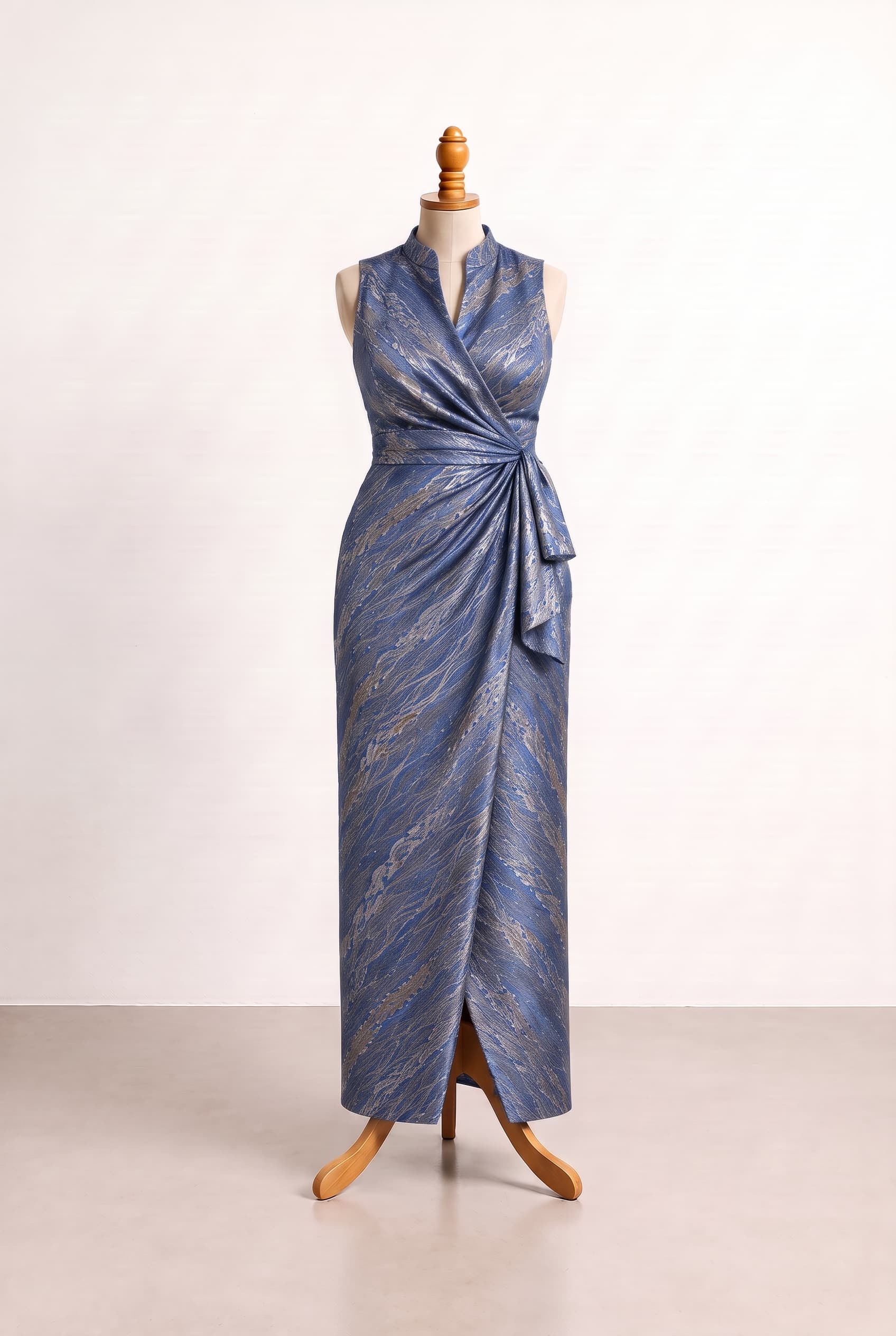 Elegant floor-length blue fitted-column gown inspired by the photo, with a shimmery patterned surface, sleeveless high stand collar flowing into a surplice V, natural waist twist, cascading drape, and a front slit; refined silver and gold accents; A fitted-column skirt with a soft cascading drape from the natural