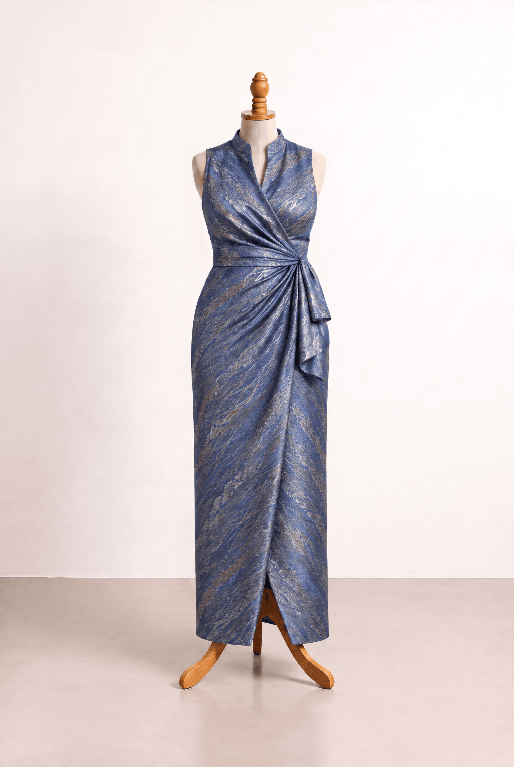 Elegant floor-length blue fitted-column gown inspired by the photo, with a shimmery patterned surface, sleeveless high stand collar flowing into a surplice V, natural waist twist, cascading drape, and a front slit. refined silver and gold accents. A fitted-column skirt with a soft cascading drape from the natural