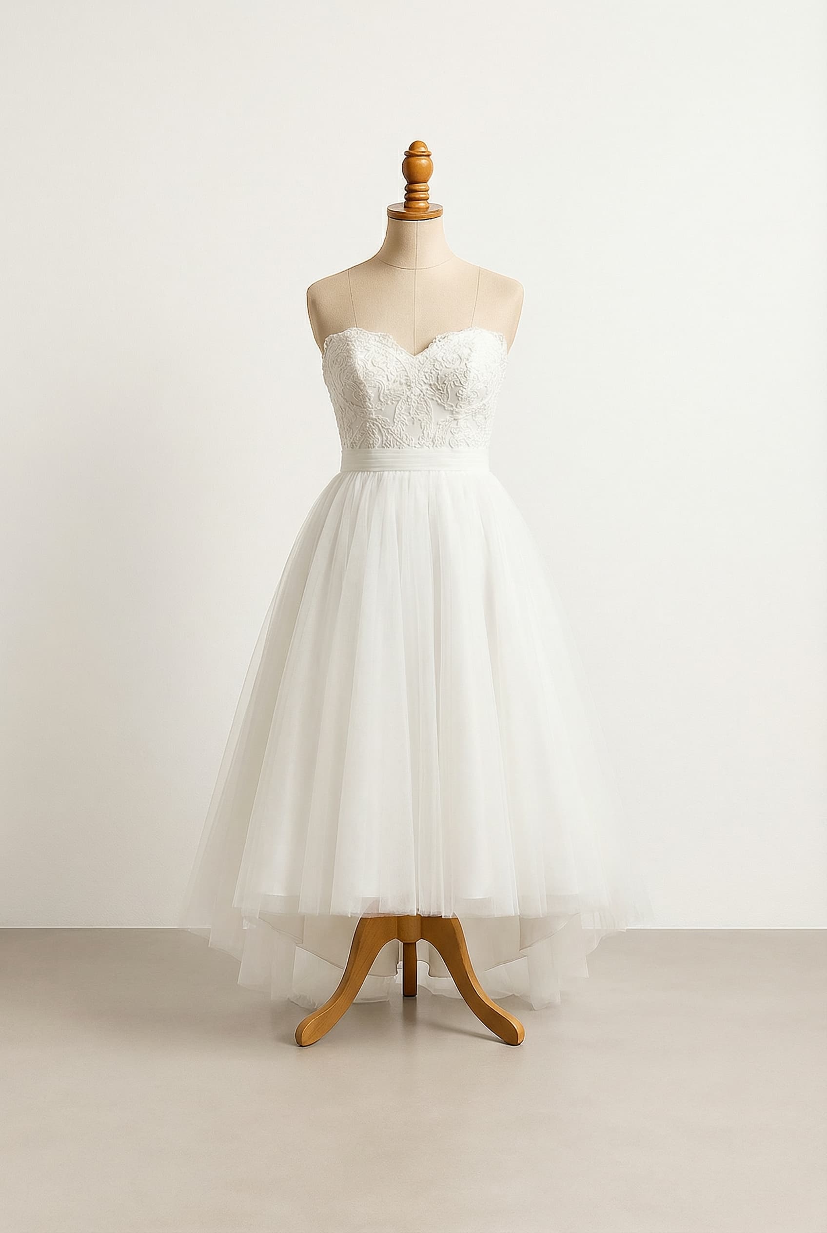A romantic wedding dress with elegant details, a high-low skirt, lace on the top, and a waist band.