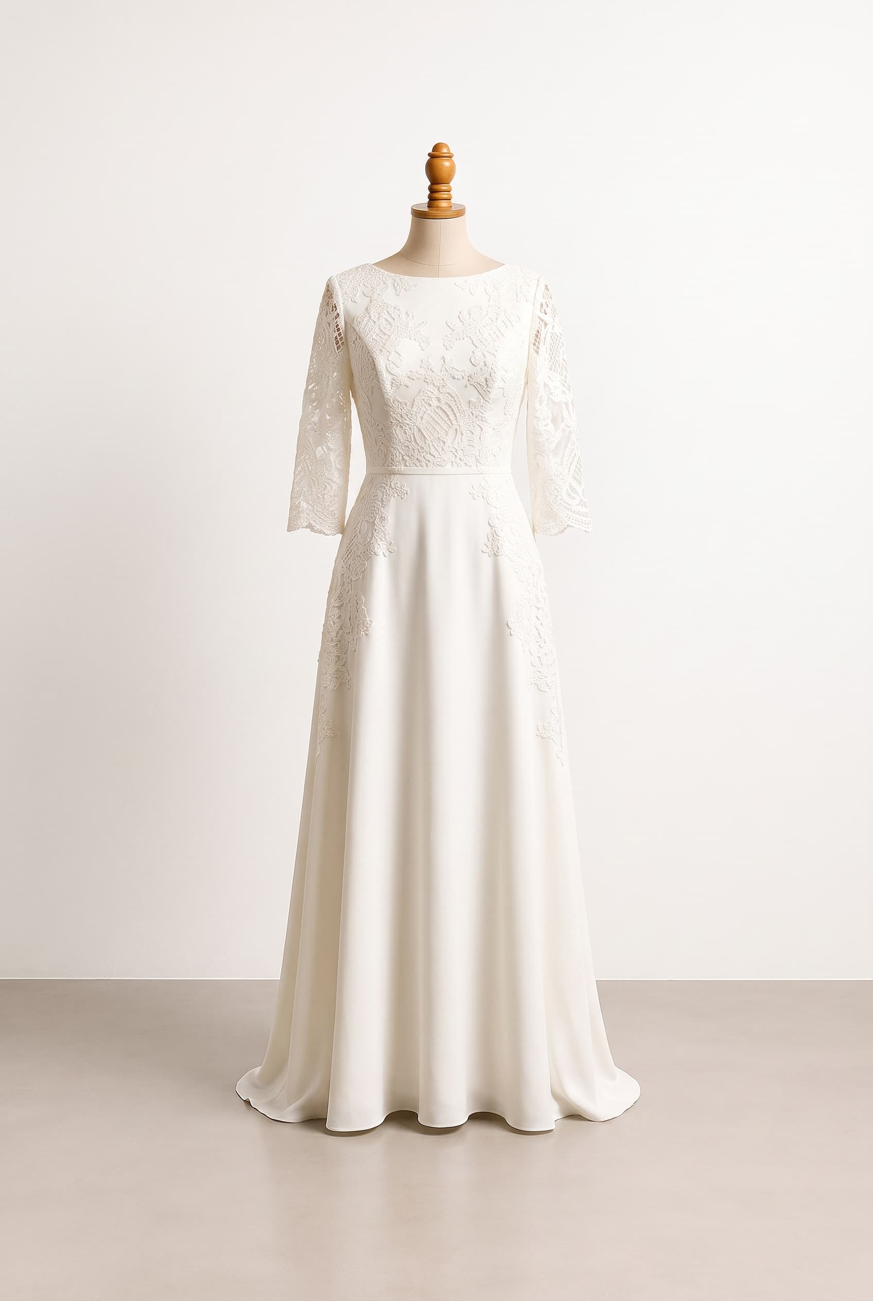 A modest wedding gown with a full-length softly structured A-line skirt, high bateau neckline, three-quarter sleeves, a defined natural waist, and delicate tonal lace appliqué over a matte ivory base; elegant, refined, and comfortable