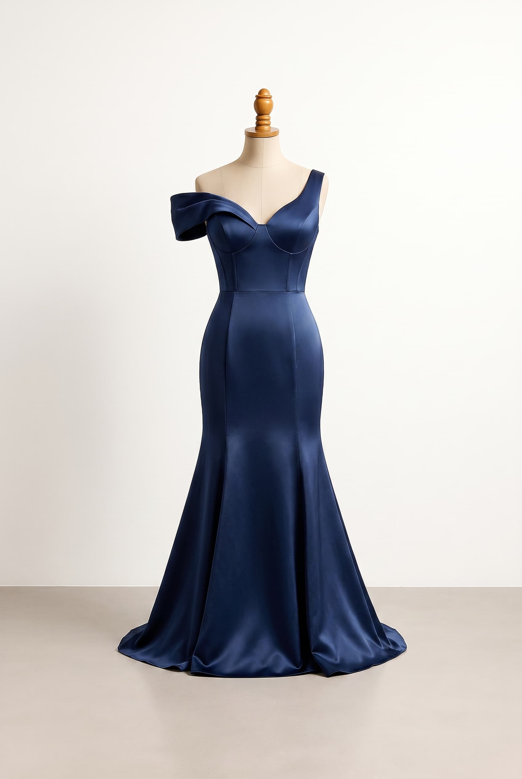 A structured, revealing prom dress designed for a grand, memorable entrance in Navy Blue. Combines opulent fabric with a daring neckline and a supportive, corset-style bodice that provides a natural push-up effect for the chest while maintaining a subtle, non-overtly corseted appearance. The dress is tight-fitted at least until the hip area. Features an asymmetrical sleeve design with one off-the-shoulder side and one sleeveless side. The skirt length is adjusted to barely graze the floor without dragging. Comfort boundary: supportive bodice with bra-friendly coverage; avoid heavy or stiff fabric; movement need: practical for walking outdoors; priority: visual drama matters most.